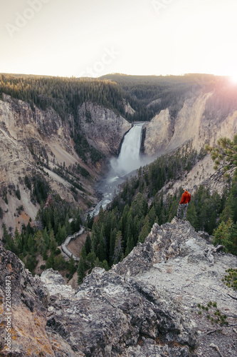 Traveler man watching over Lower Yosemite falls at the sunset