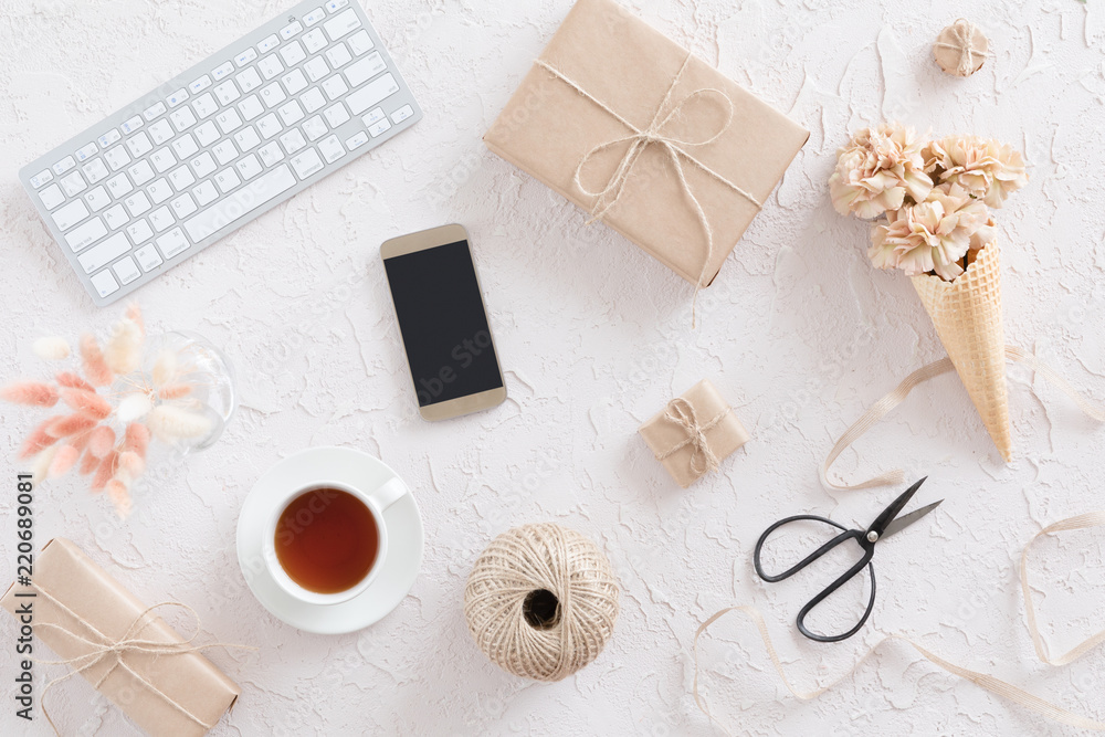 Top view of woman workspace with laptop, beige flowers, smartphone on white textural background, flat lay. Stylish female blogger concept. Top view of woman workspace with laptop, beige flowers, smartphone on white textural background, flat lay. Stylish female blogger concept.
