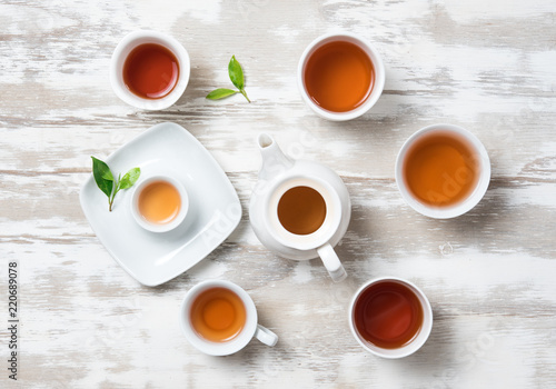 Tea concept,Teapot and cup of herbal tea with green tea leaves on wood,top view