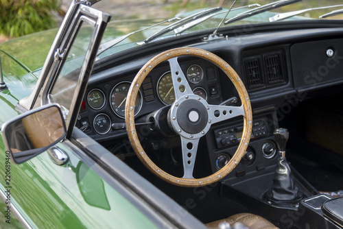 view into an green oldtimer convertible car with a wooden steering wheel