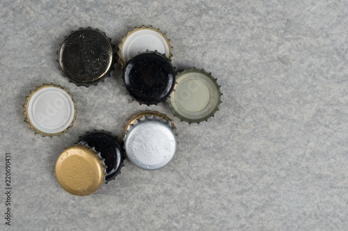 Beer bottle caps on grey concrete textured copy space background