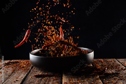 Fototapeta Naklejka Na Ścianę i Meble -  Pouring cayenne pepper powder into the bowl on wood table,Motion blur