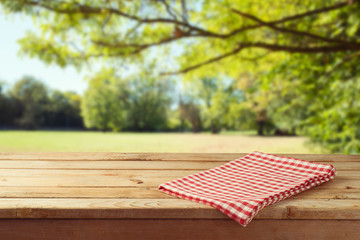 Empty wooden table with tablecloth over autumn nature park background