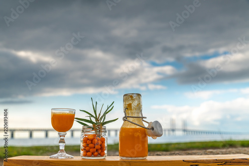 Sea buckthorn is an orange super berry with lots of vitamins 
and good for health with Oresunds bridge in the back ground and a cloudy day photo