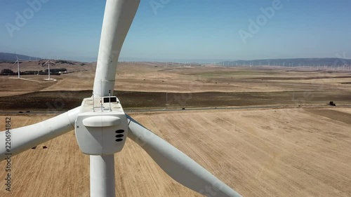 Molino eolico dentro de un campo de cultivo en un dia soleado junto a la carretera grabado con dron photo