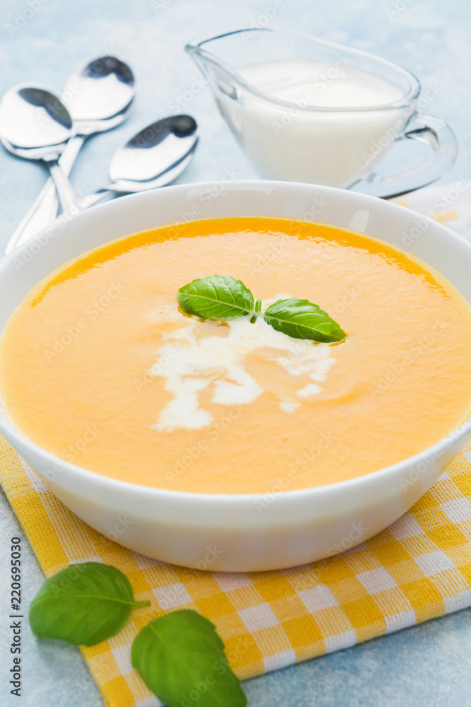 Pumpkin soup with basil on blue background Pumpkin soup with basil on blue background