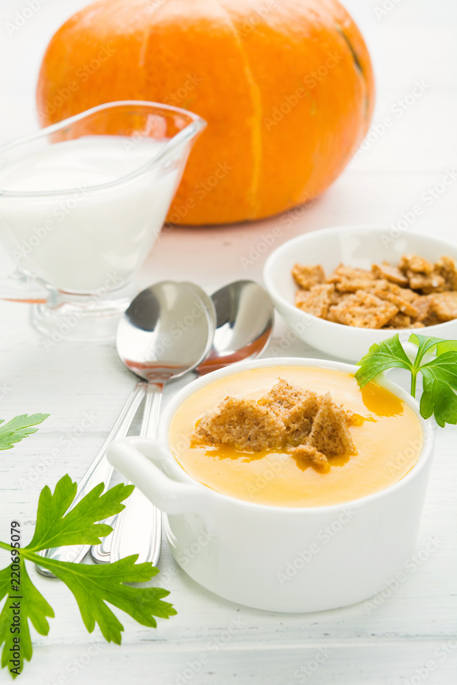 Pumpkin cream soup with croutons on white wooden table Pumpkin cream soup with croutons on white wooden table