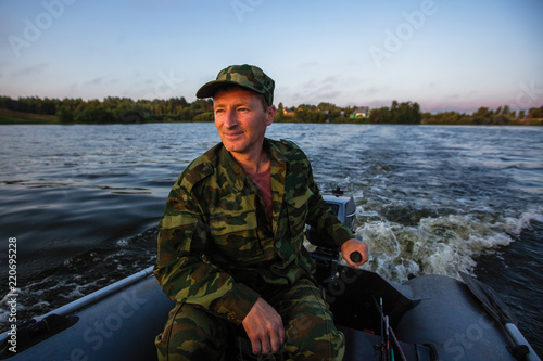 Fisherman on rubber motor boat floats on the lake.
