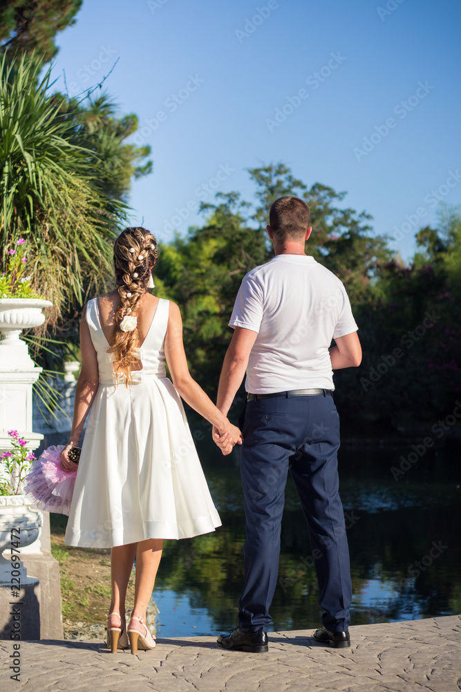 Newlyweds stand with their backs by the pond