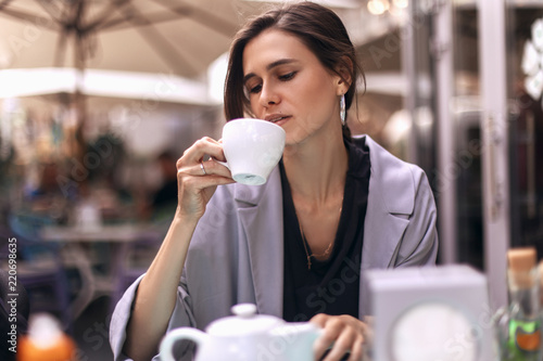 Attractive brunette bussines woman with tail drinking coffee or tea in restaurant. cofee break