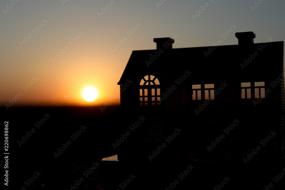 decorative small metallic house on the sunset background. Selective focus