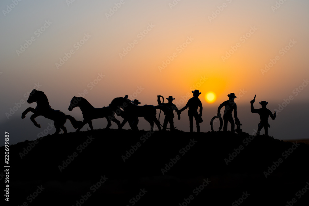 Cowboy concept. Silhouette of Cowboys at sunset time. A cowboy silhouette on a mountain with an yellow sky.