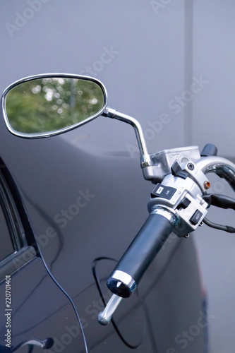 Motorcycle  parked next to the car. View of the dashboard and the steering wheel with rear-view mirrors.