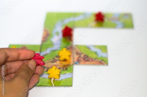 Close up red and yellow meeples in hand isolated on white background. Components of board games. Small figures of people's body in hand. Vacation time. Gameplay.
