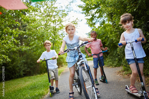 Group of kids riding bike and scooter