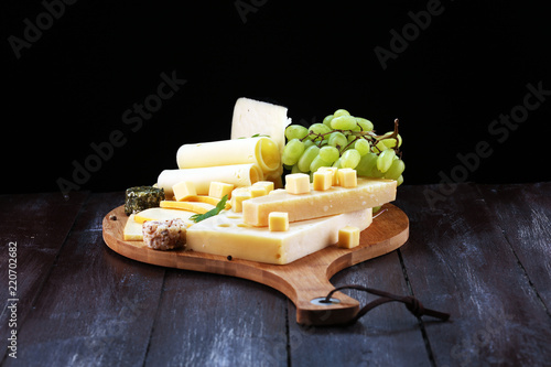 Cheese platter with different cheese and grapes.