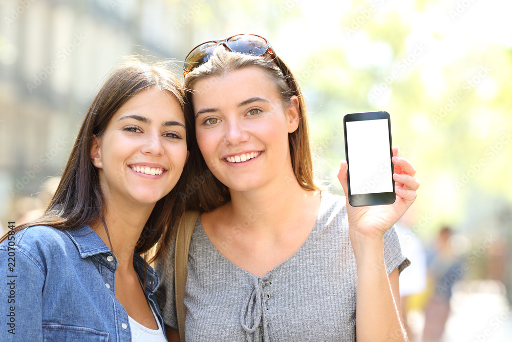 Two happy friends showing a smart phone screen Two happy friends showing a smart phone screen