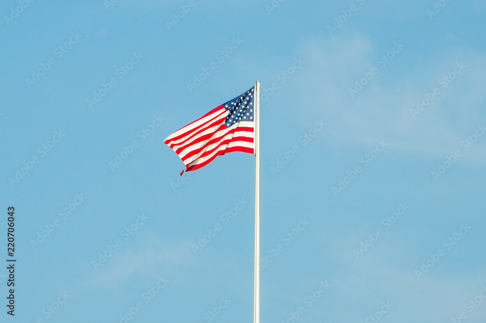 Waving USA flag on blue sky.