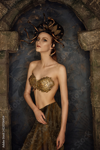 girl costume jellyfish gorgon with gold bra from scales in a stone arch photo