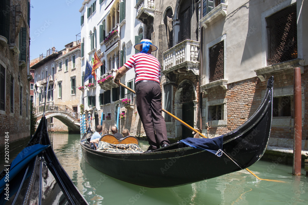 Venice, Italy - May 21, 2017: The gondola floats along the old narrow street in Venice. Gondola is the most attractive tourist transport in Venice.