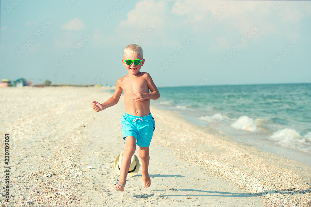 The boy is running along the beach. A happy summer vacation.