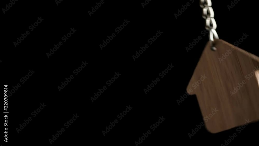Wooden key holder with house shape hanging and rotating on black background Wooden key holder with house shape hanging and rotating on black background