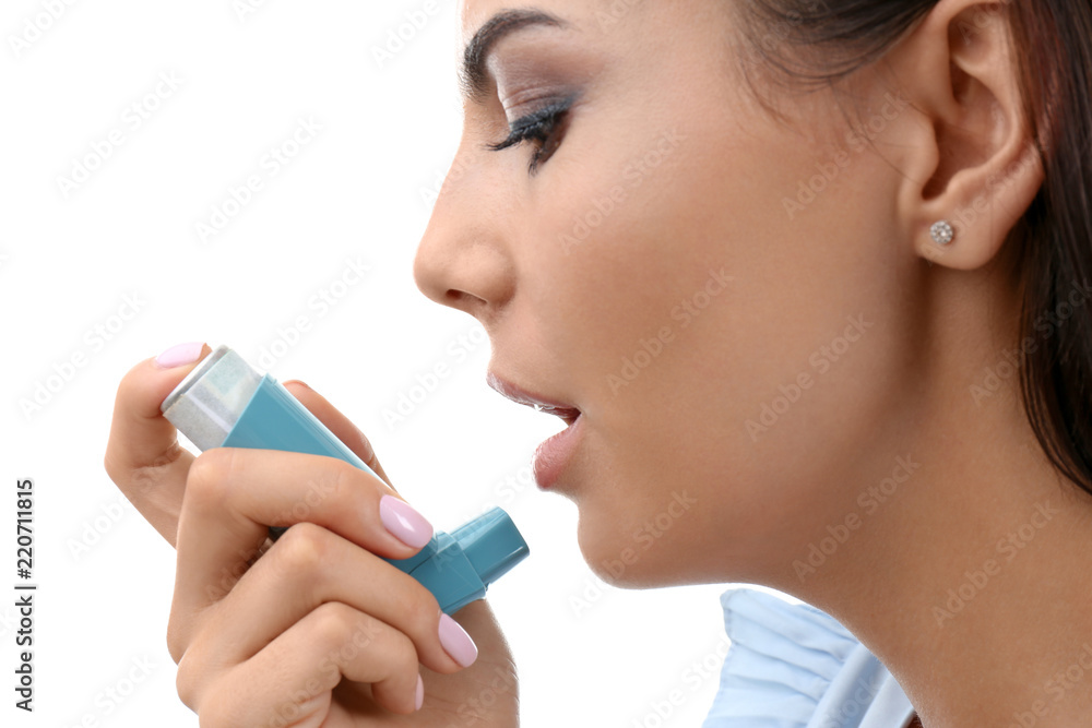 Young woman using asthma inhaler on white background, closeup Young woman using asthma inhaler on white background, closeup