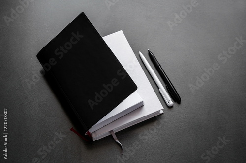 Business concept. Office dark table. Mock up book blank black, leather cover for magazine, booklet, brochure, diary, business portfolio mock-up design template on black background. Flat lay, top view 