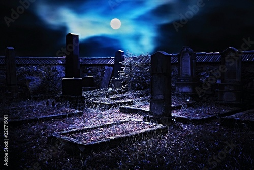 Old Jewish cemetery with stone tombstones, moonlit full moon. Scary night scenery.