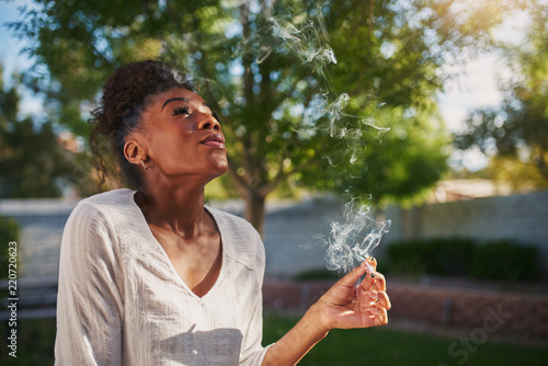Canvas Print happy african american woman smoking marijuana joint in back yard
