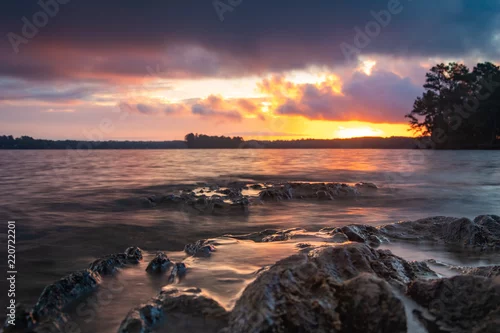 Obraz Wschód / zachód słońca nad skalistym jeziorem