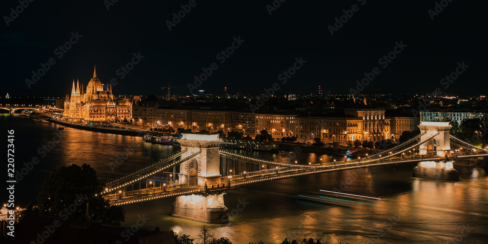 Panoramic view of Danube river, Széchenyi Chain Bridge, and the Parliament building at night (long exposure, night trails) Budapest Hungary
