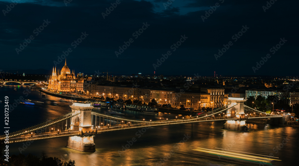 Fototapeta premium Panoramic view of Danube river, Széchenyi Chain Bridge, and the Parliament building at night (long exposure, night trails) Budapest Hungary