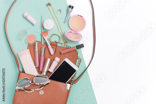 Beauty and cosmetic products spilling out of a woman's handbag.