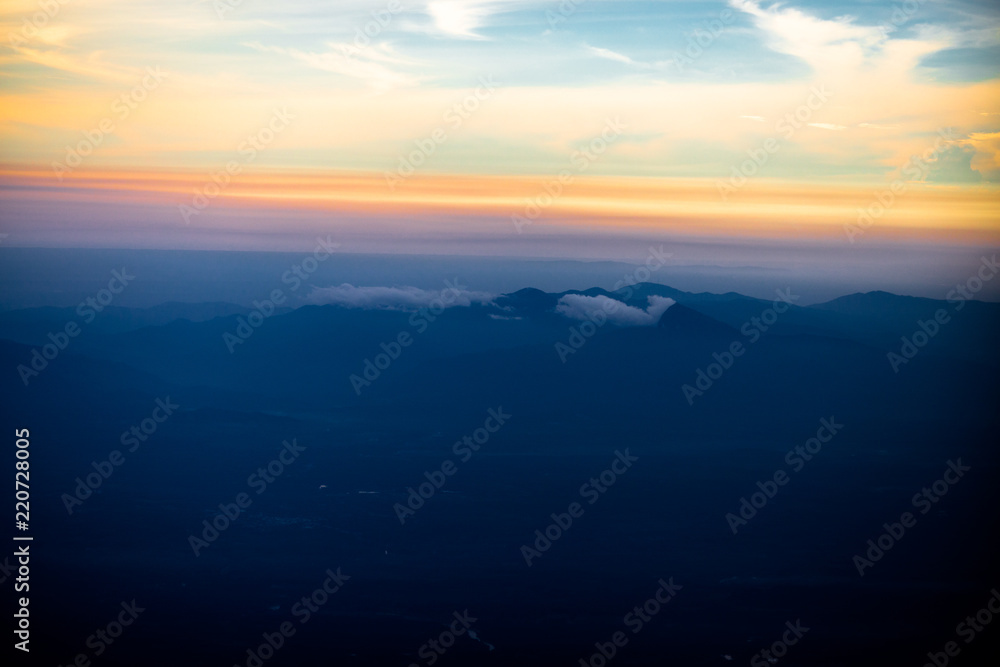 Fototapeta premium Background, high angle from the passenger plane. You can see the scenery by the distance (mountains, rivers, sky, fog, houses), the photos may be blurred during the flight.
