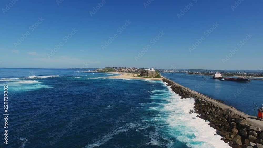 a pullback aerial shot of nobbys head lighthouse and breakwall in newcastle, australia a pullback aerial shot of nobbys head lighthouse and breakwall in newcastle, australia