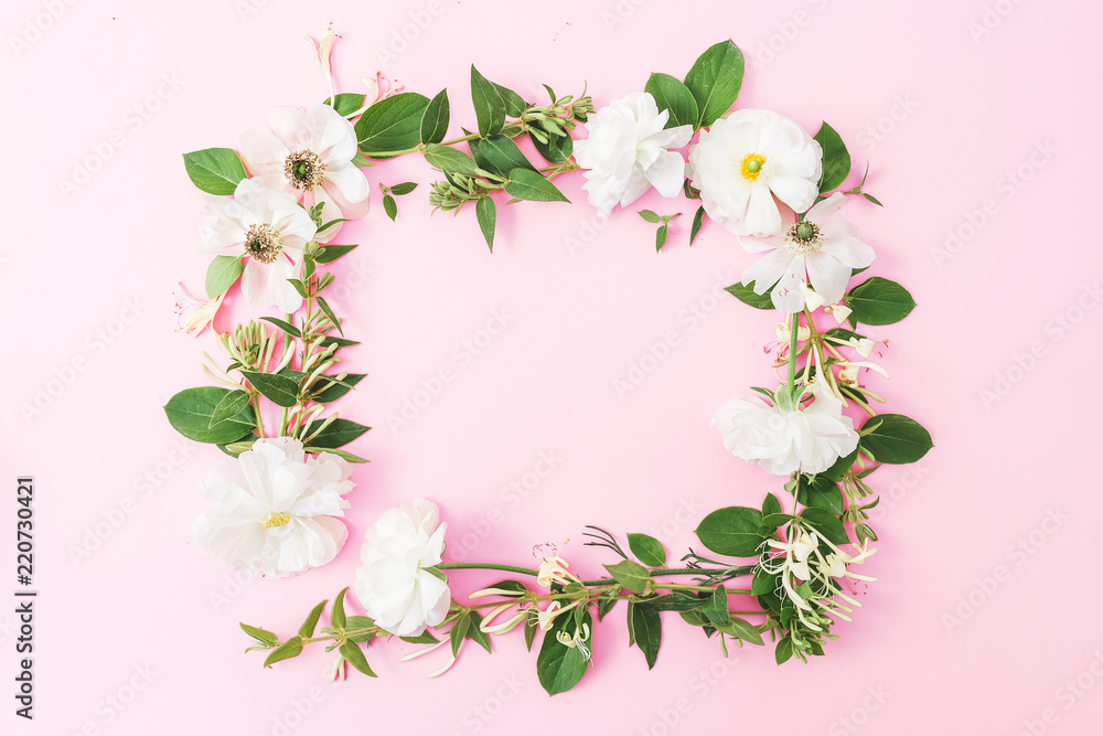 Frame of white flowers and leaves on pink pastel background. Flat lay, top view. Copy space