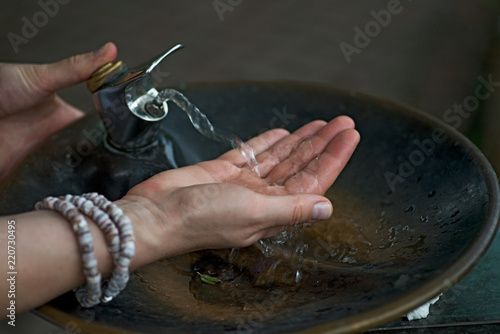Water from drinking fountain flows into woman's hand in botanic garden.