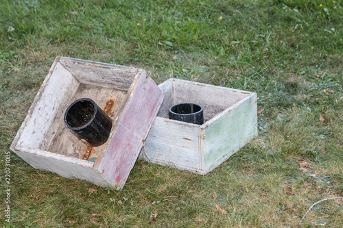 Washer toss game boxes sit on the grass in the summer sunshine.