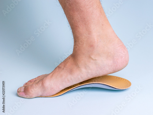 The right leg of a man with a strong flat feet trying on an orthopedic insole.