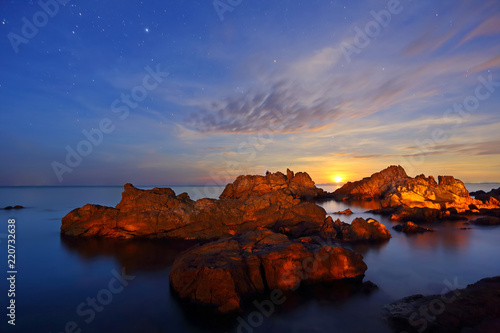 Long Exposure of stars, the moon is falling with rocks and sea in the dawn © isarescheewin