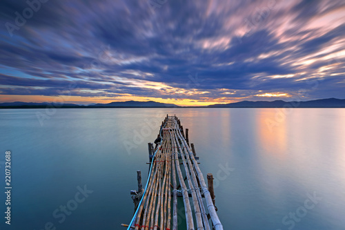 Long Exposure of clouds with long bamboo bridge on the water sea in the sunrise 