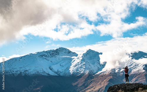 A young lady photographer with a stunning  scenery of rocky mountain covered with snow after the raining day. Cloudy and foggy. Diamond lake track, Wanaka, New Zealand. © Klanarong Chitmung