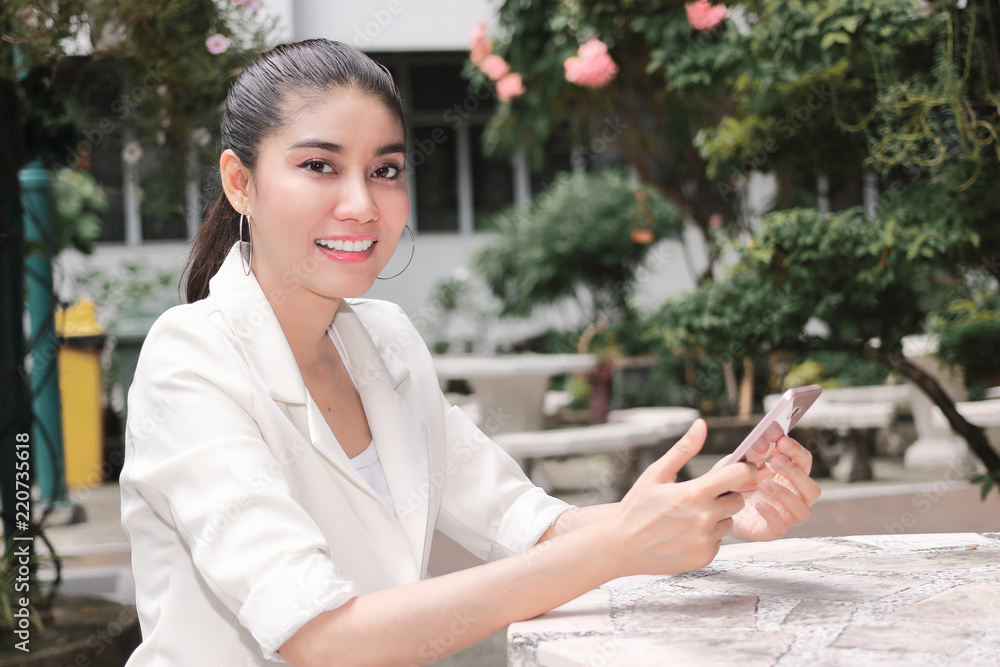 Smiling young Asian woman using mobile smart phone. Internet of things concept Smiling young Asian woman using mobile smart phone. Internet of things concept