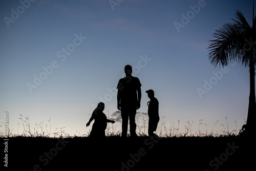 Silhouette of a man, a woman and another man- outdoors © Mateus