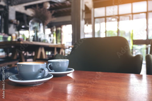 Closeup image of two blue cups of hot latte coffee on vintage wooden table in cafe