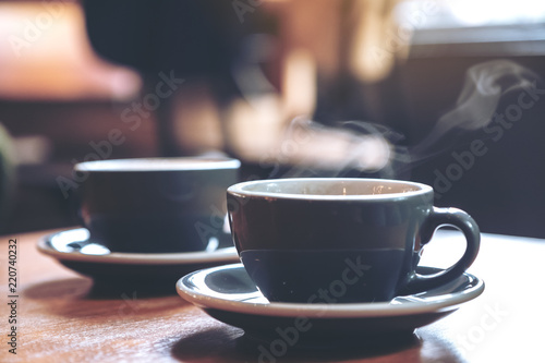 Closeup image of two blue cups of hot coffee on vintage wooden table in cafe
