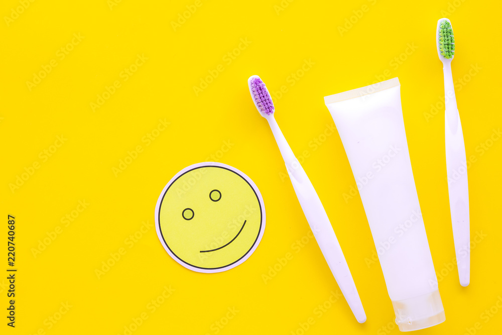 Teeth care, dental care. Toothbrushes and tooth paste near smile face emoji on yellow background top view copy space Teeth care, dental care. Toothbrushes and tooth paste near smile face emoji on yellow background top view copy space