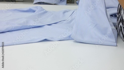 seamstress in the sewing shop checks for quality and defects shirt. a textile factory worker with a pair of scissors removes the unnecessary threads and defects from clothing