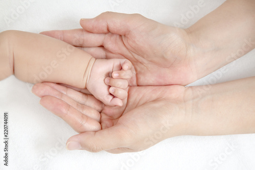 赤ちゃんの小さな手を包むお母さんの大きな両手のアップ。成長と健康を喜ぶ母。母性、愛情、幸せ、育児、健康のイメージ